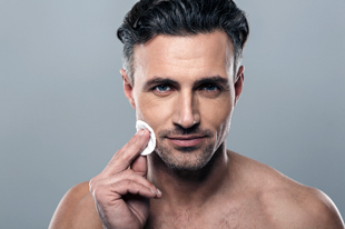 man applying skincare product to face with cotton pad demonstrating 8 essential steps for healthy skin