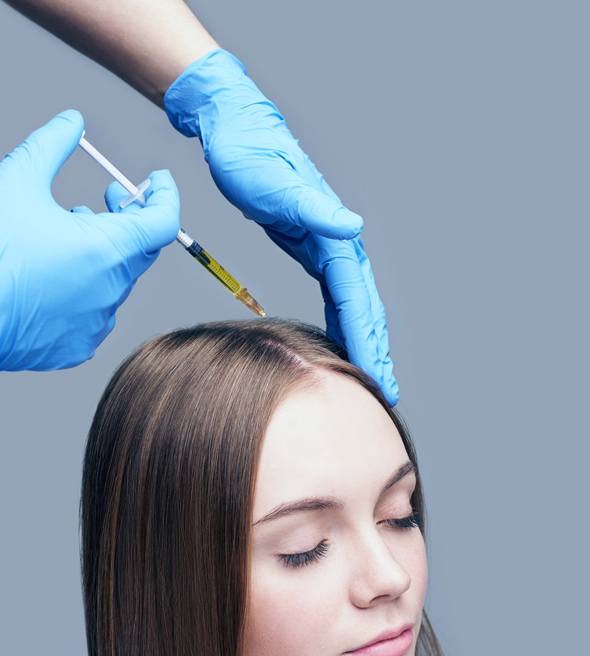 hands in blue gloves administering hair treatment injection to woman's scalp for hair restoration