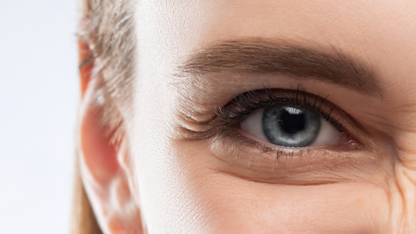 close-up of a woman's blue eye highlighting eyelashes and eyebrow with a hint of aging and expression featuring beauty and skincare tips 4 essential practices