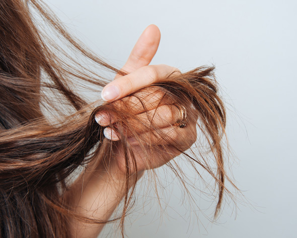 a person holding strands of long hair demonstrating hair care techniques and hair health tips