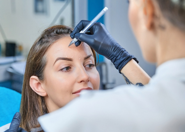 beautician applying cosmetic treatment on client with focused expression in modern salon professional eyebrow shaping procedure