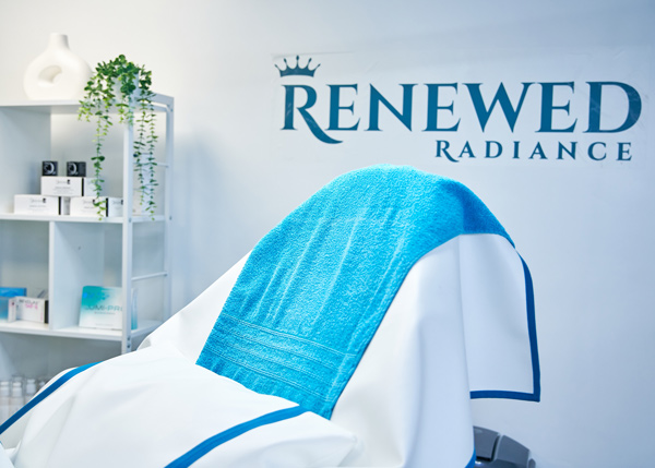 treatment room with blue towel and Renewed Radiance sign for skincare services