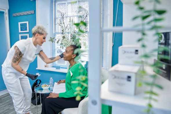 beautician applying treatment to a client in a spa setting with plants and products suggesting beauty and skin care 2 options available