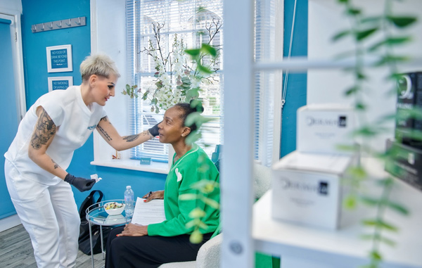 professional skincare treatment session with a beauty expert and client in a bright blue room featuring plants and skincare products for glowing skin and beauty routine 2